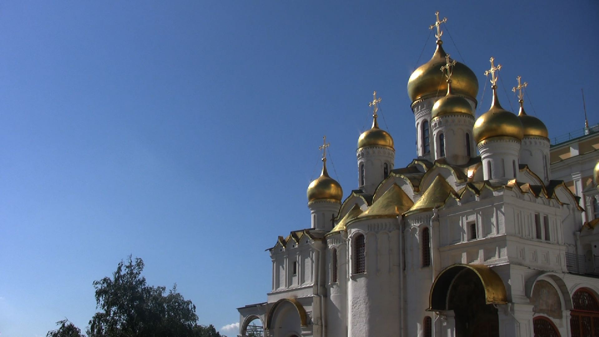 Weiße Kathedrale mit goldenen Kuppeln vor tiefblauem Himmel im Moskauer Kreml.