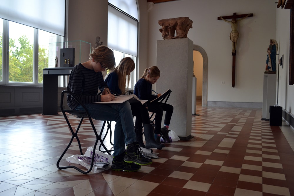 Kinder zeichnen im Museum auf Klapphockern