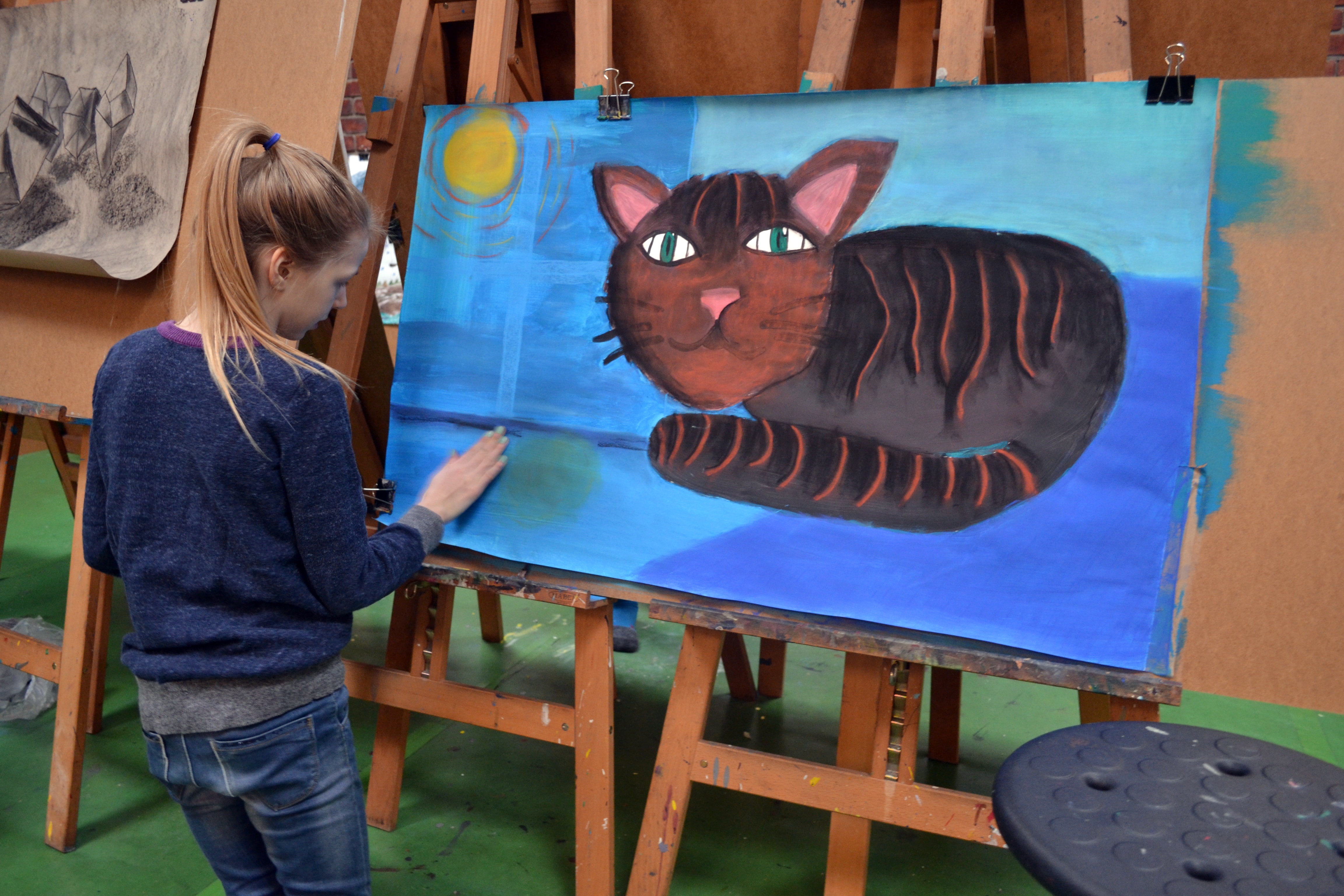Mädchen malt eine große Katze an der Staffelei