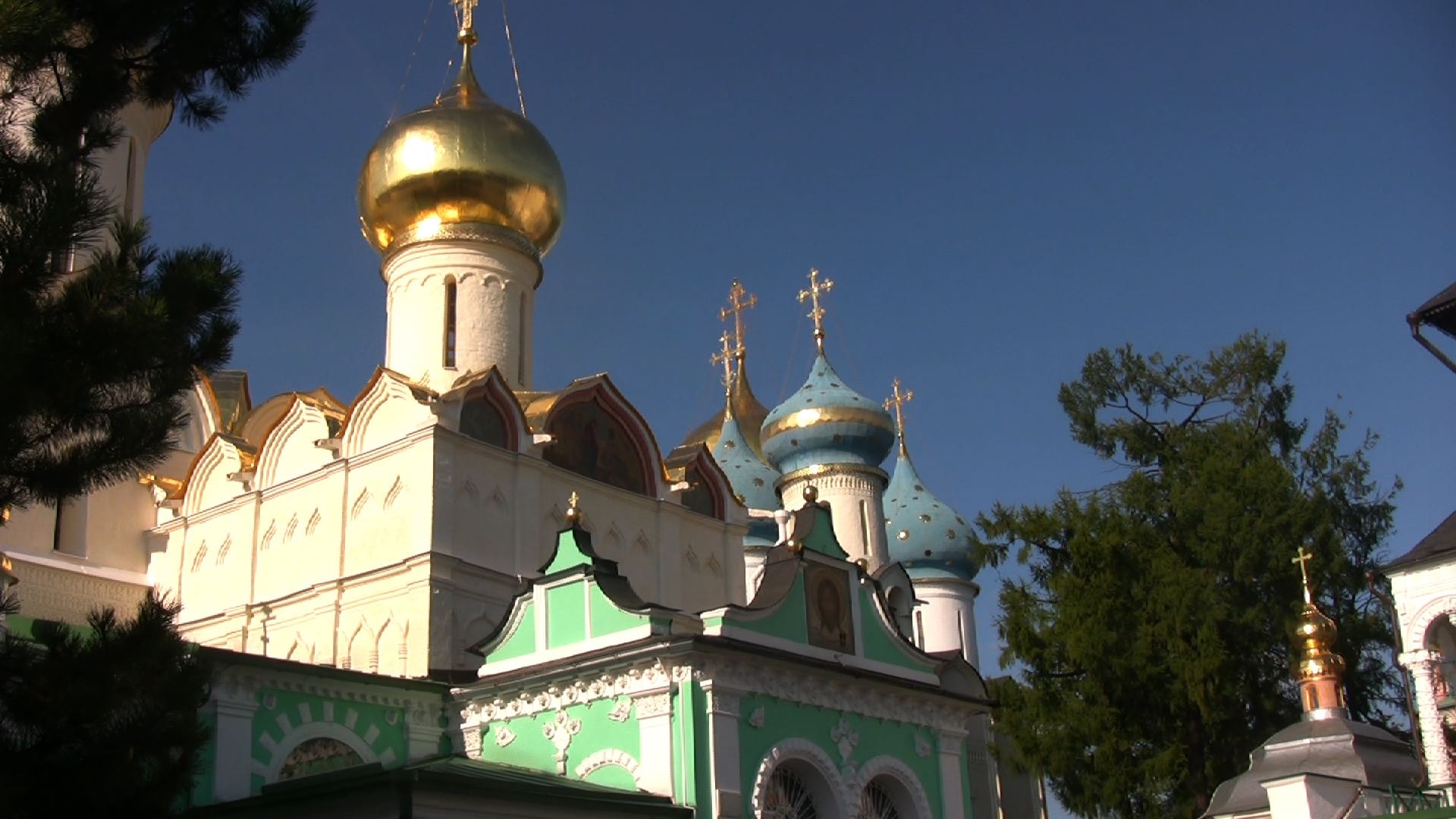 Goldene und blaue Zwiebeltürme eines russischen Klosters vor blauem Himmel.