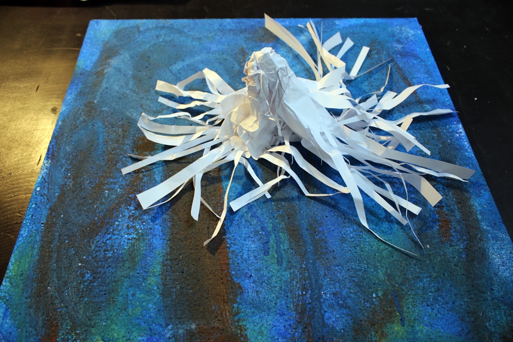 Vogel aus Papier auf blau bemaltem Grund